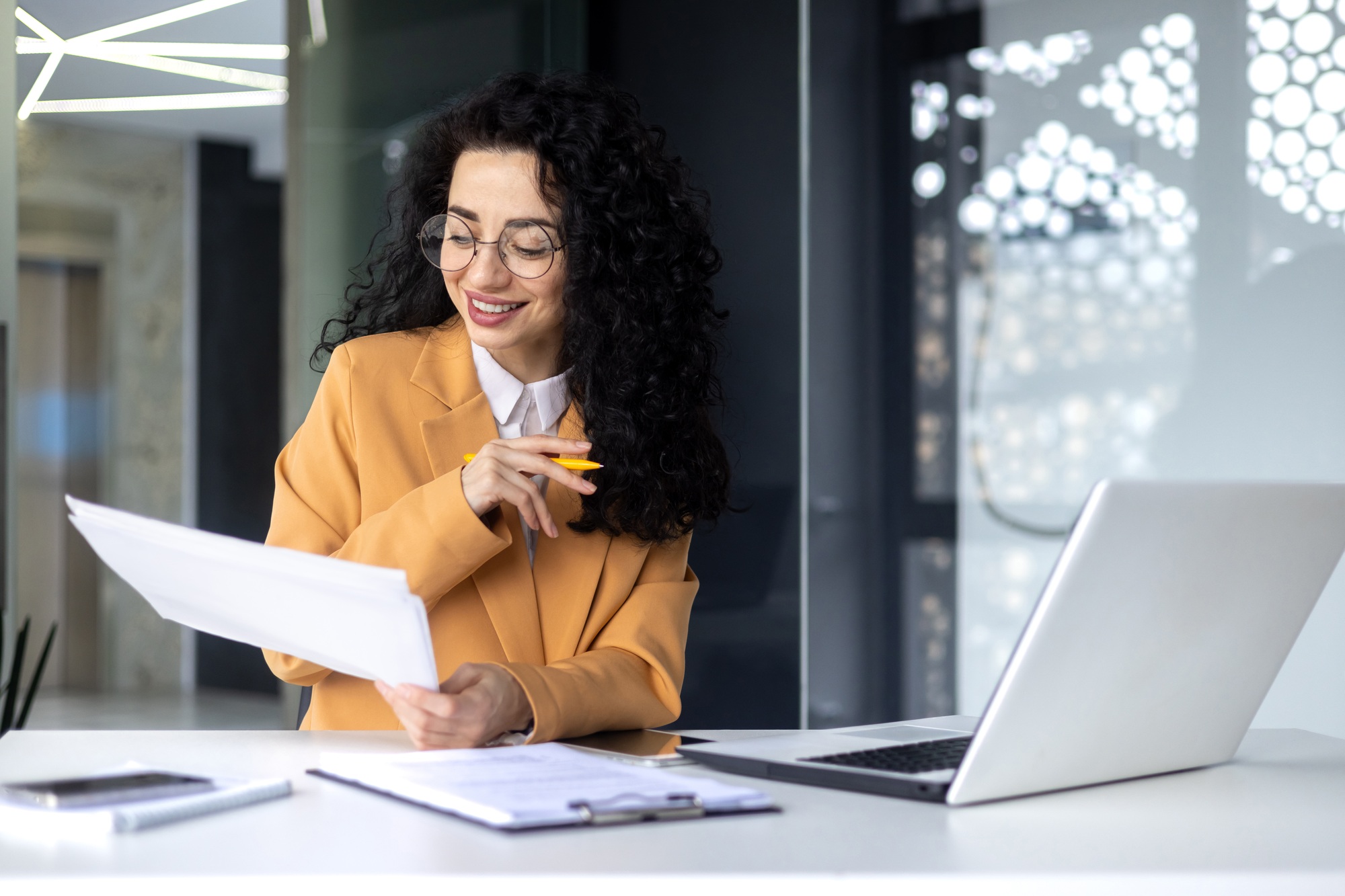 latin american businesswoman working inside office with documents and laptop, worker paperwork